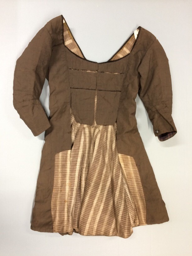 A Woman’s jacket made of dark brown wool with split vest panels and lined with brown-and-white striped linen